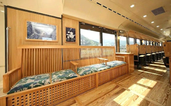 Kyushu rail train interior with wooden seating and scenic window views.