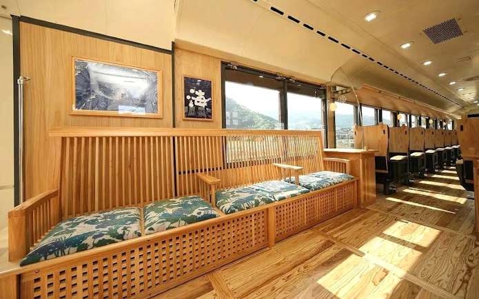 Kyushu rail train interior with wooden seating and scenic window views.