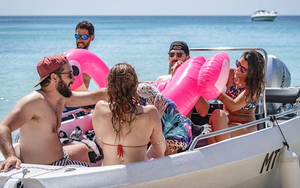 Group enjoying a private boat tour with inflatable flamingo in Arrábida Natural Park.