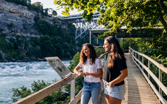 Two girls reading an informational sign at White Water Walk, Niagara Falls.