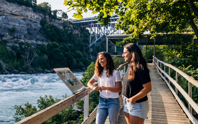 Two girls reading an informational sign at White Water Walk, Niagara Falls.