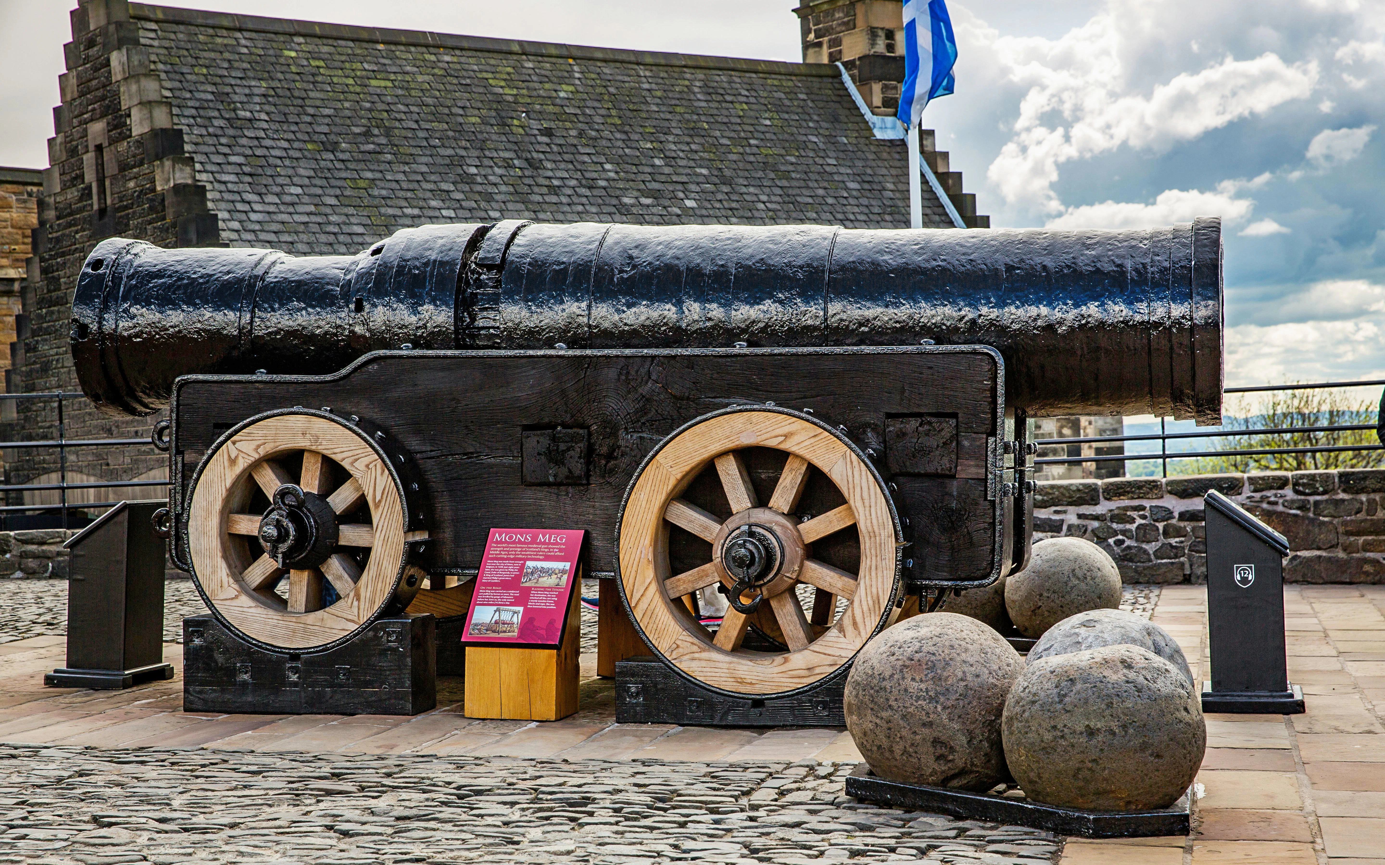 Mons Meg cannon at Edinburgh Castle with cannonballs and informational plaque.