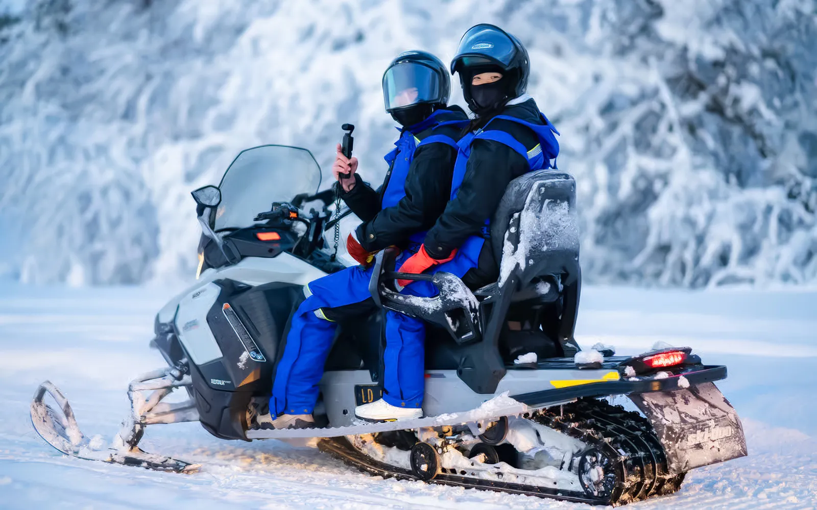 Two people on a snowmobile during a small-group day trip in snowy Tromso.