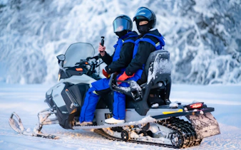 Two people on a snowmobile during a small-group day trip in snowy Tromso.