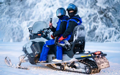 Two people on a snowmobile during a small-group day trip in snowy Tromso.
