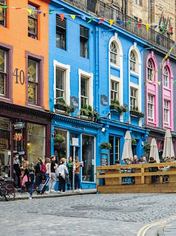 Colorful buildings and tourists on Victoria Street, Edinburgh, associated with Harry Potter.