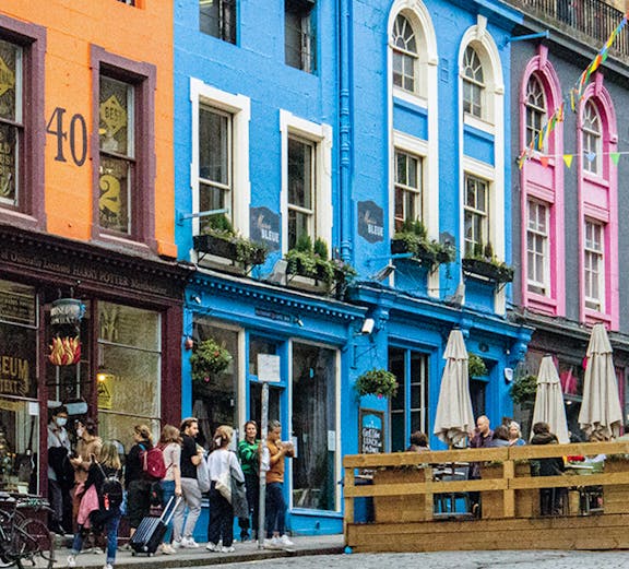 Colorful buildings and tourists on Victoria Street, Edinburgh, associated with Harry Potter.