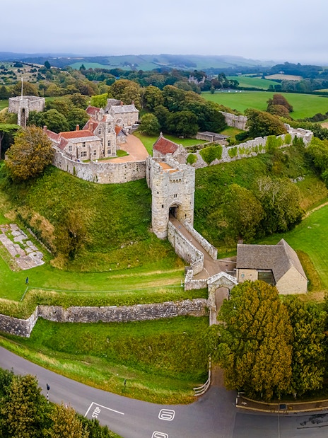 Aerial view of Carisbrooke Castle, Isle of Wight, surrounded by lush greenery and historic walls.