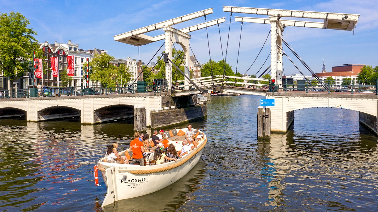 Boat tour crossing Skinny Bridge on Amsterdam's canal.