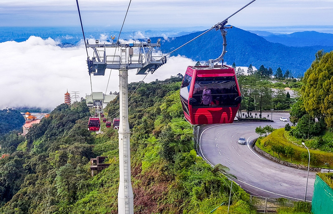 Genting Awana Cable Car ascending over lush forest with mountain views.