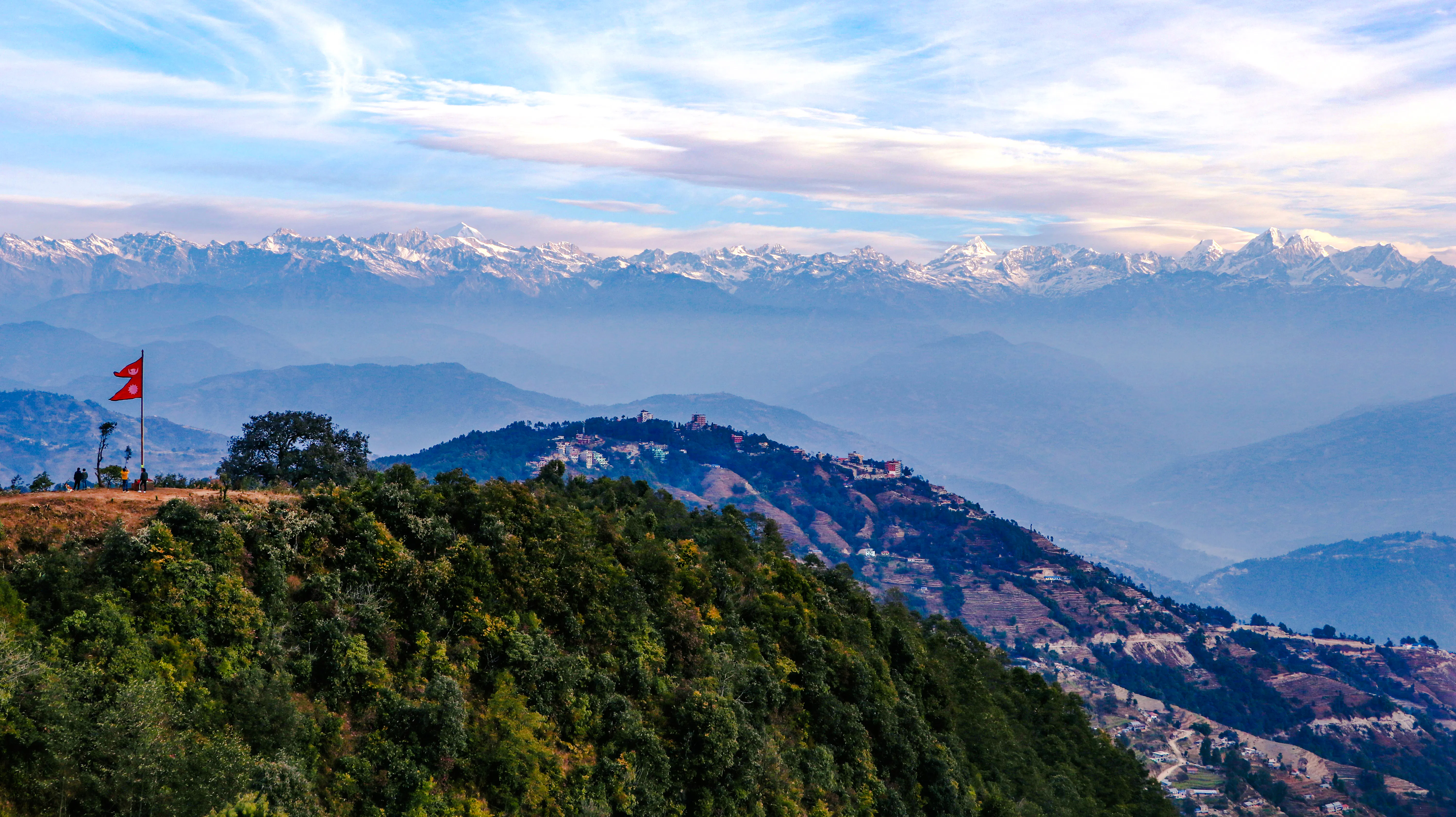 Sunrise view of the Himalayas from Nagarkot with hikers and Nepal flag, Kathmandu.