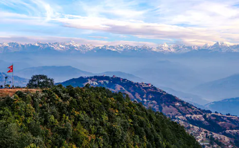 Sunrise view of the Himalayas from Nagarkot with hikers and Nepal flag, Kathmandu.