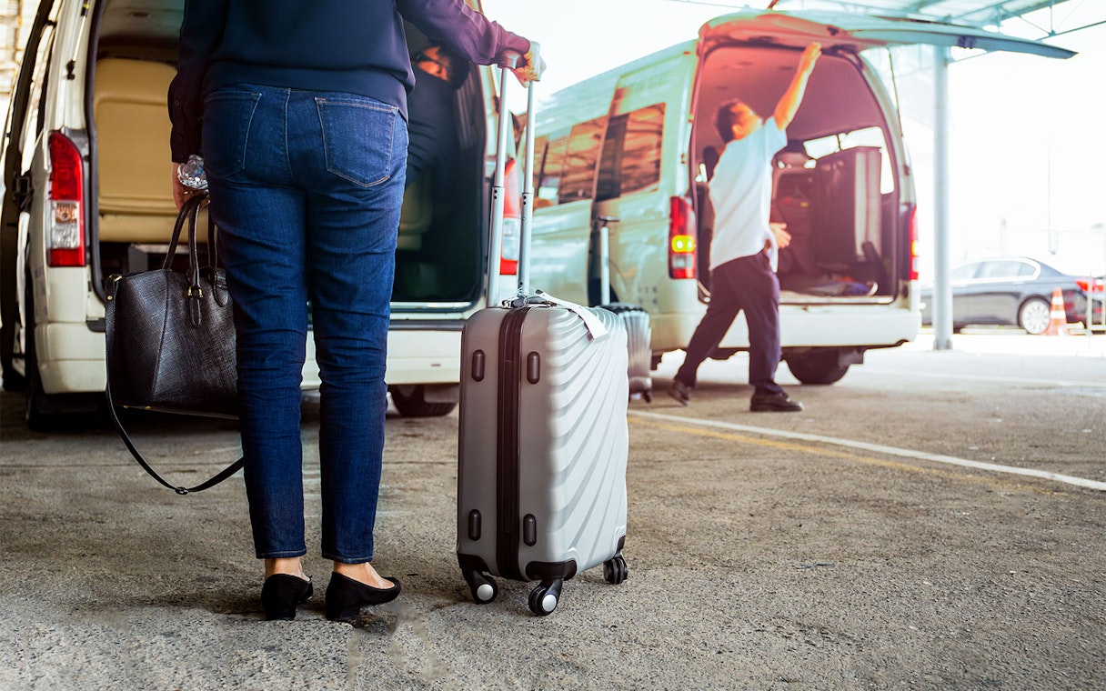 Traveler with luggage near van for Tawau Airport transfer.