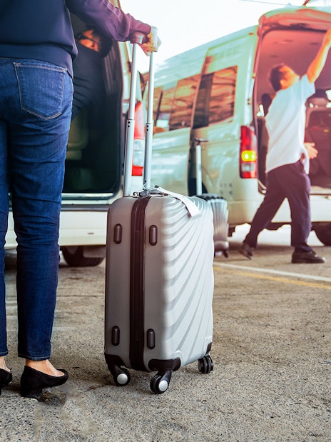 Traveler with luggage near van for Tawau Airport transfer.