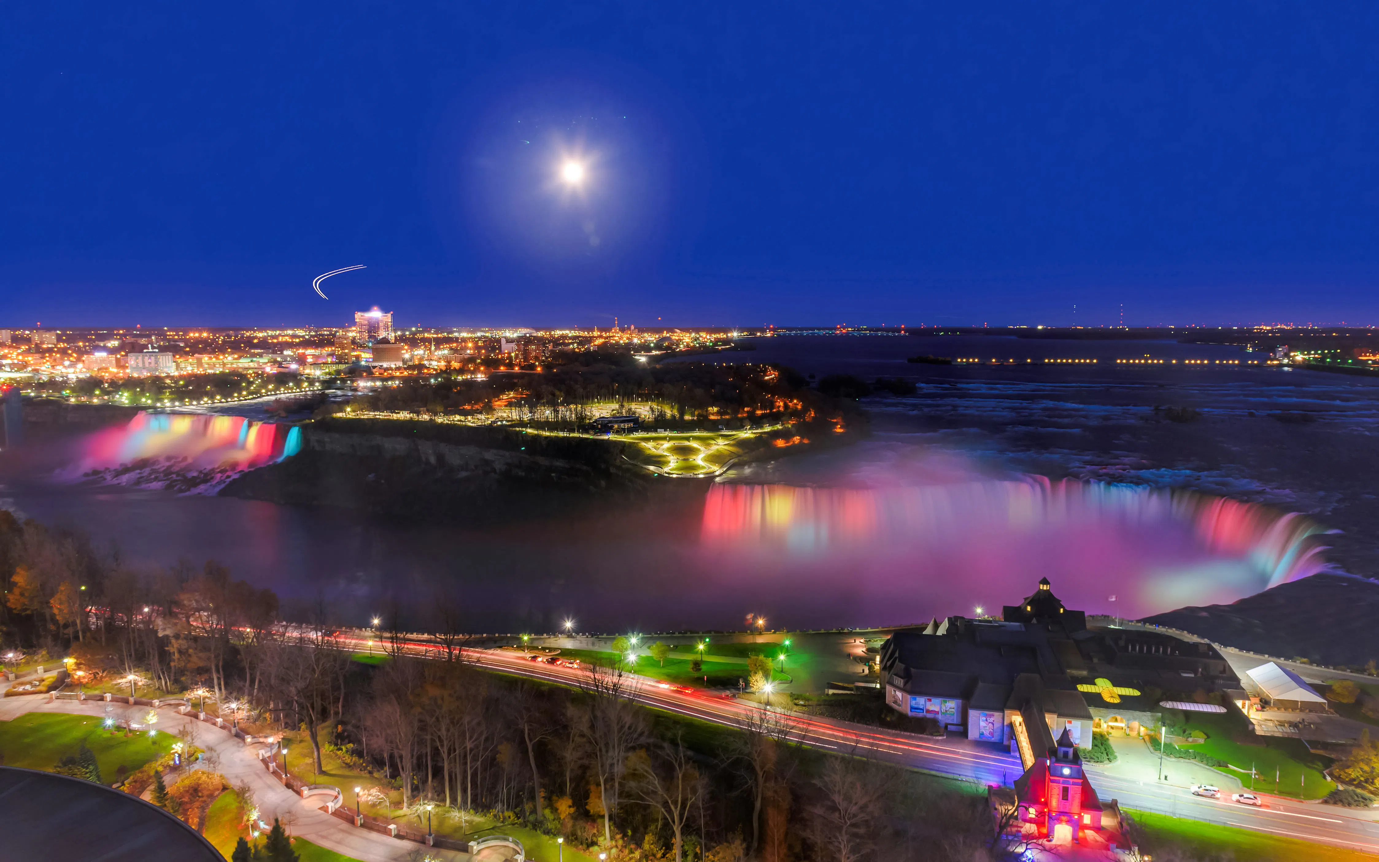 Niagara Falls illuminated at night with city lights in the background, Canada.