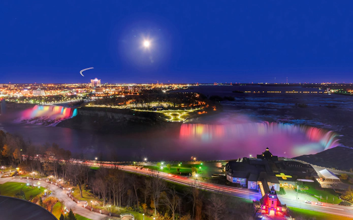 Niagara Falls illuminated at night with city lights in the background, Canada.