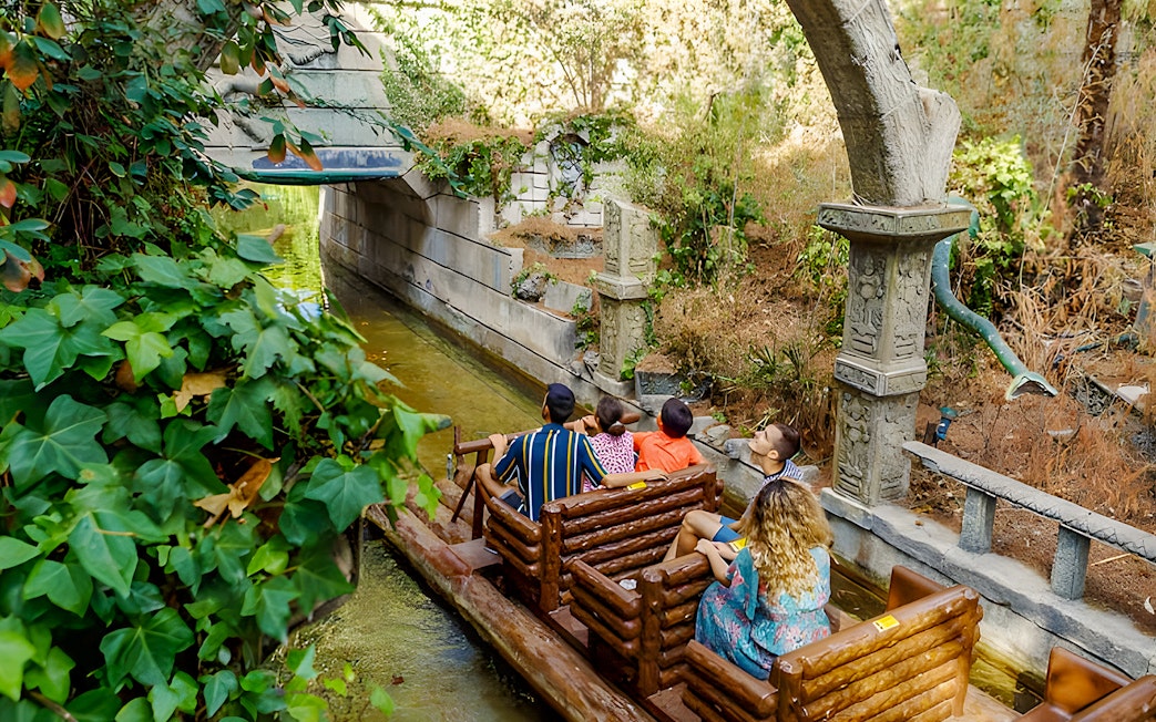 Visitors on a log ride through lush greenery at Parque de Atracciones de Madrid's The Jungle.
