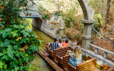 Visitors on a log ride through lush greenery at Parque de Atracciones de Madrid's The Jungle.