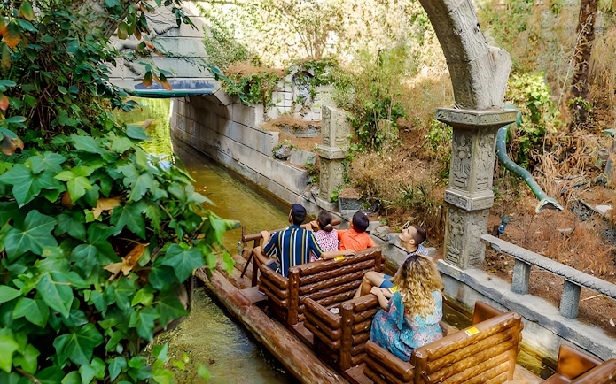 Visitors on a log ride through lush greenery at Parque de Atracciones de Madrid's The Jungle.