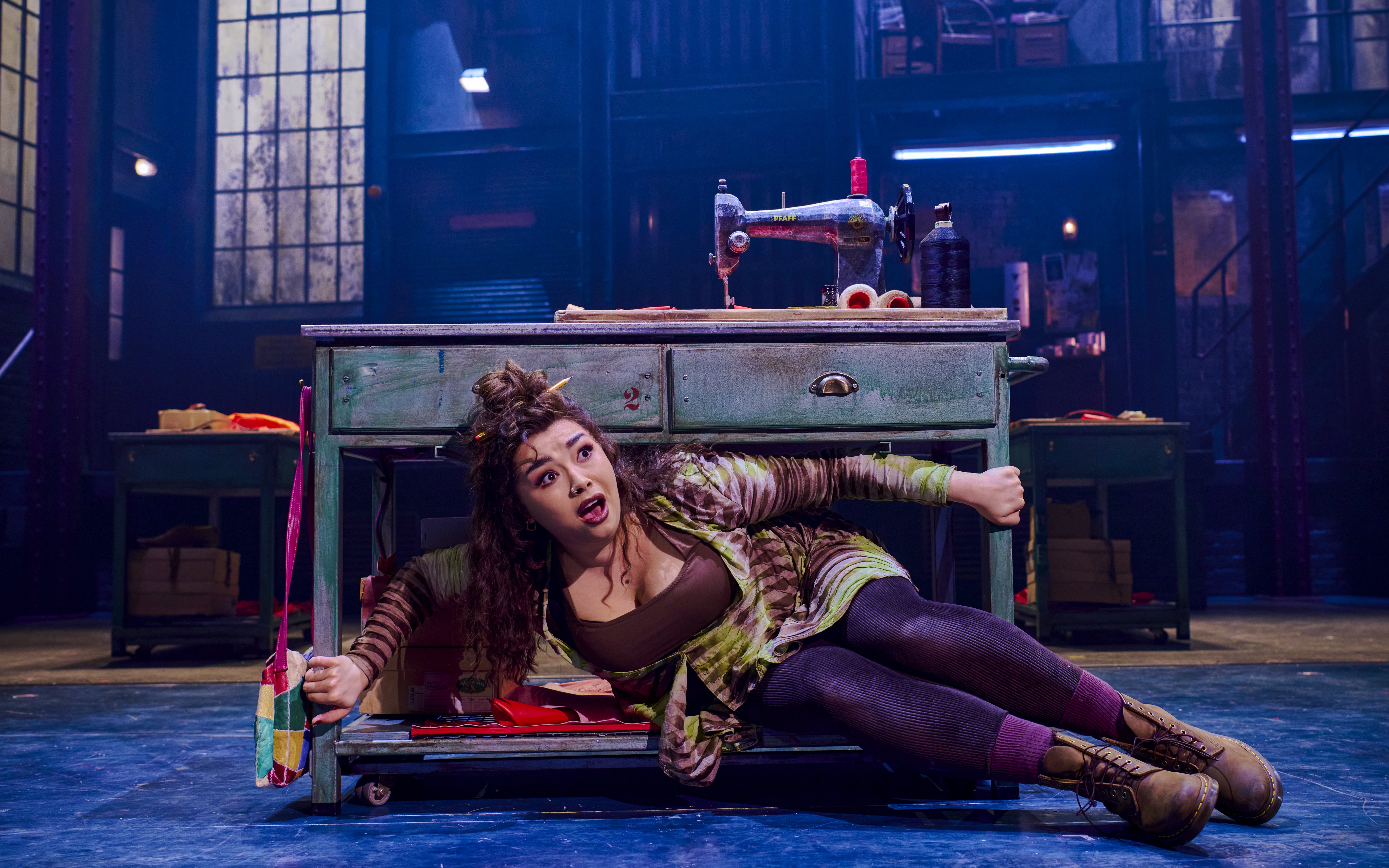 Performer under sewing table during Kinky Boots production.