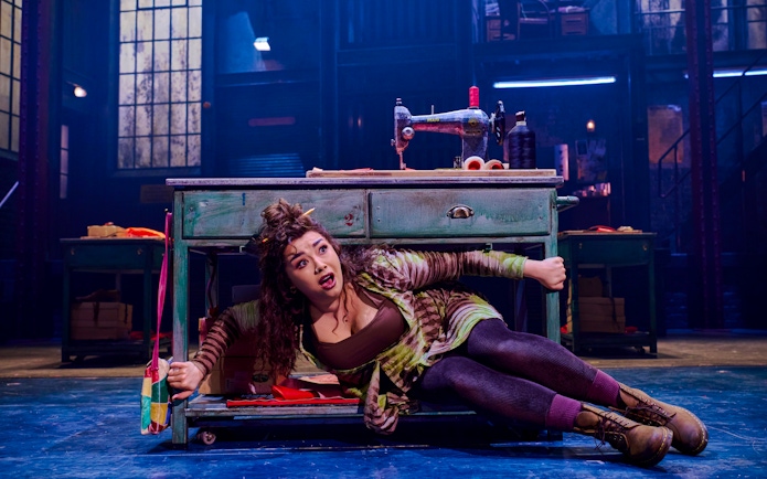 Performer under sewing table during Kinky Boots production.