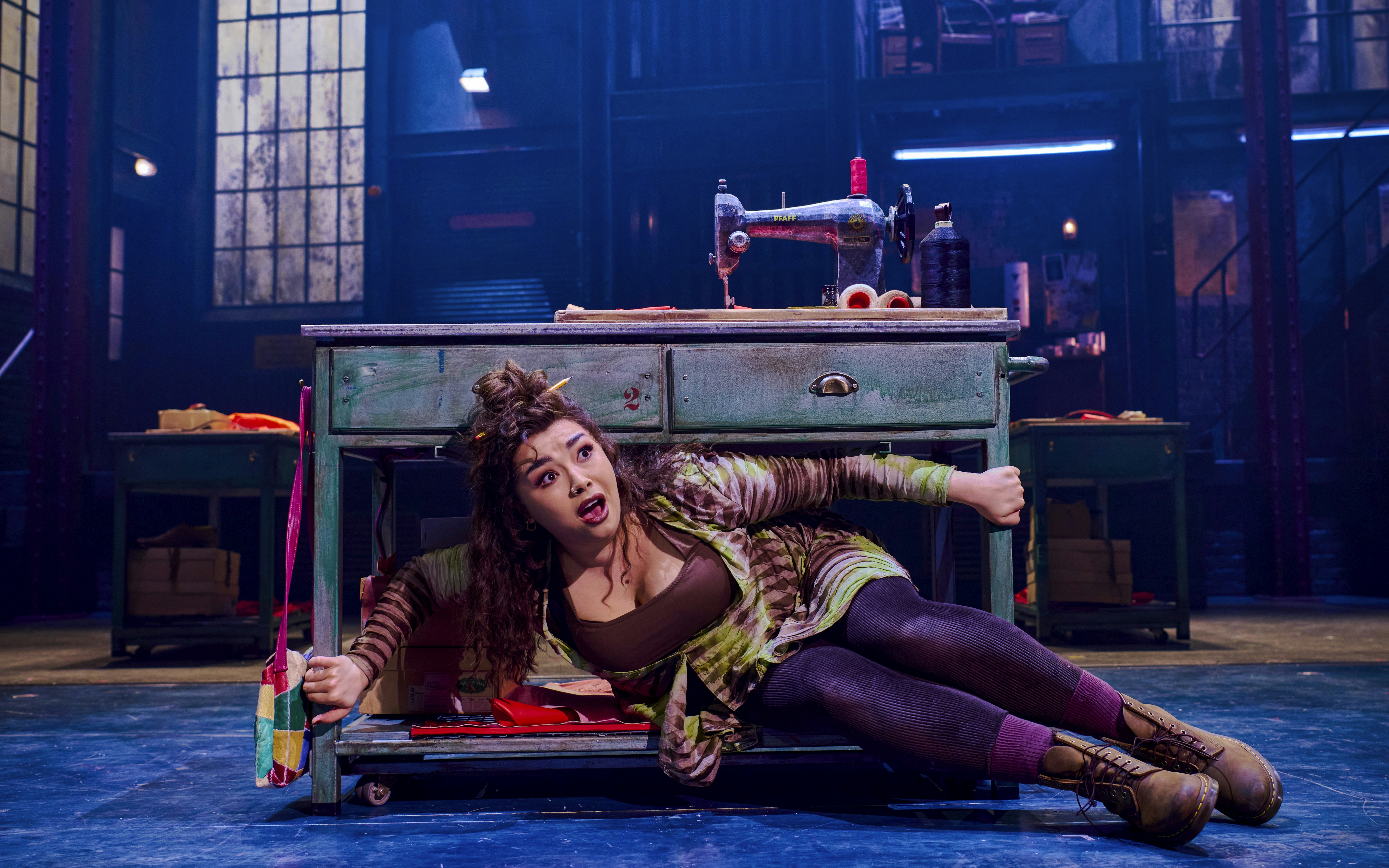 Performer under sewing table during Kinky Boots production.