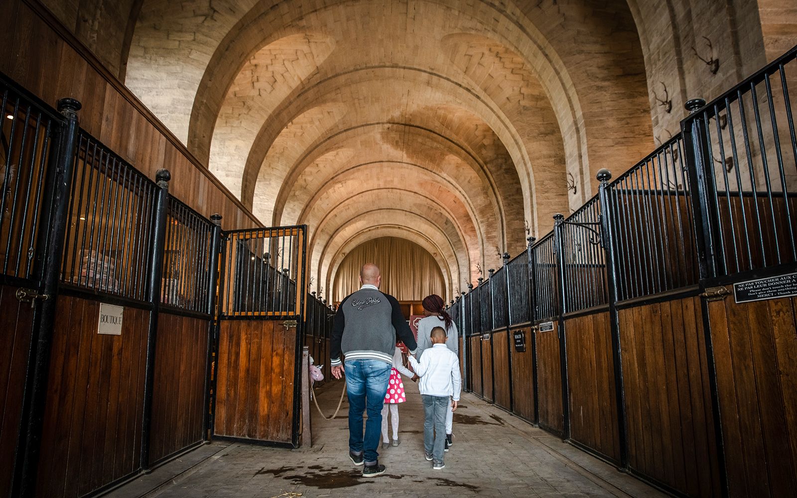Family walking through the stables of Chateau de Chantilly, France.