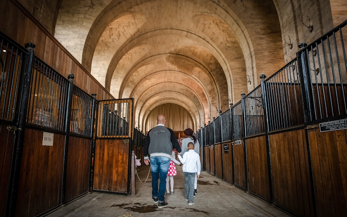 Family walking through the stables of Chateau de Chantilly, France.