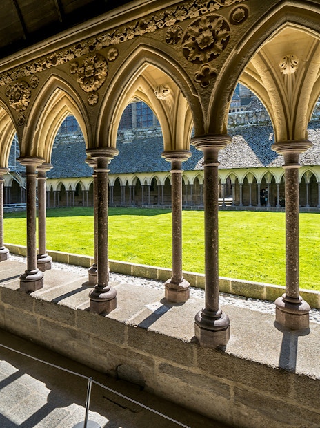 Cloister arches at Mont St. Michel with view of the courtyard lawn.