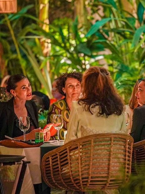 People dining at Nouba Marrakech surrounded by lush greenery.