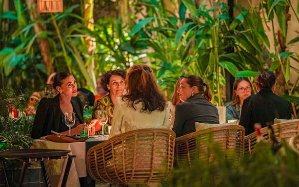 People dining at Nouba Marrakech surrounded by lush greenery.