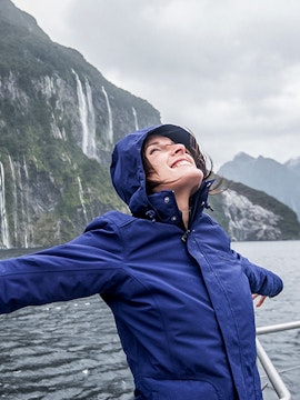 Person enjoying a Doubtful Sound cruise with waterfalls in the background.