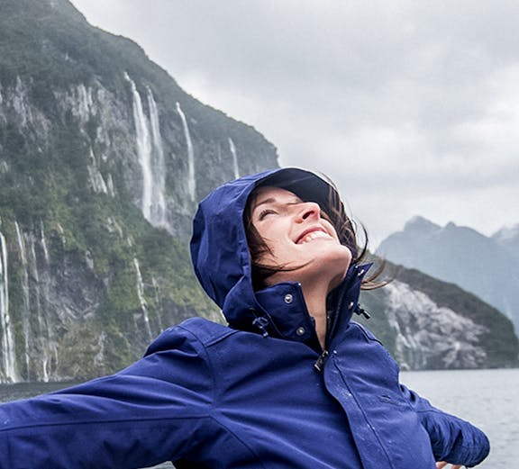 Person enjoying a Doubtful Sound cruise with waterfalls in the background.