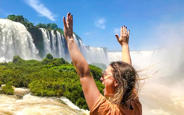 Visitor enjoying the view of Brazilian Falls with arms raised.