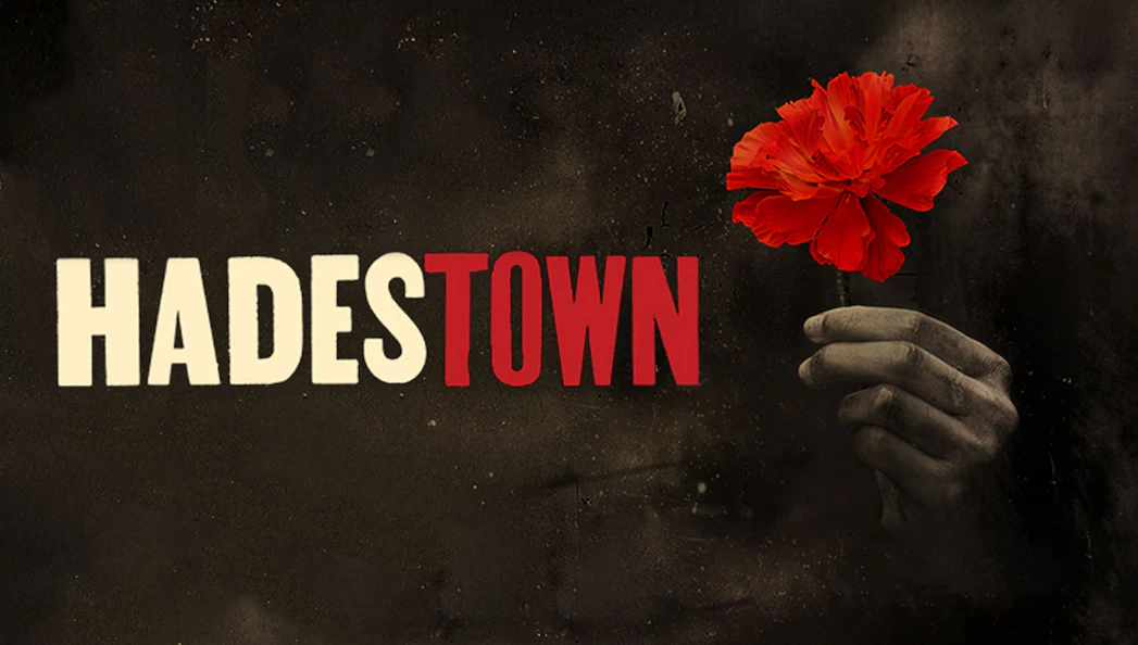 Hand holding red flower next to Hadestown musical title