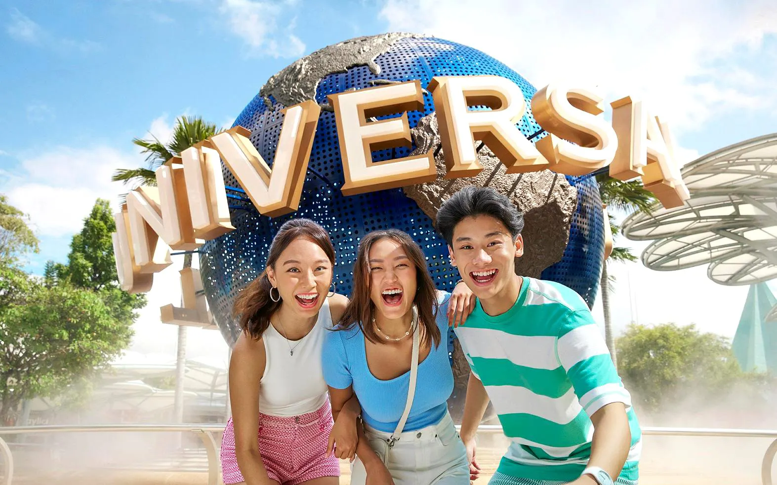 Visitors smiling in front of the Universal Studios Singapore globe.