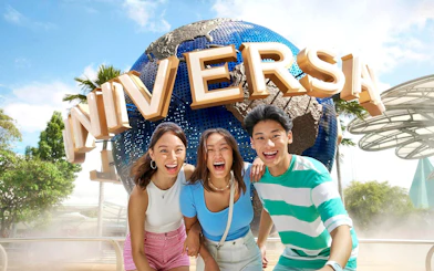 Visitors smiling in front of the Universal Studios Singapore globe.