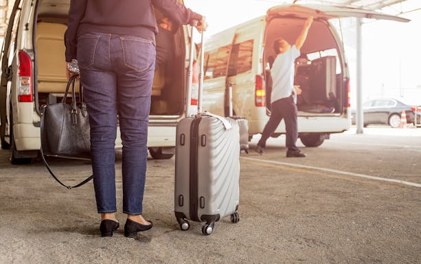 Traveler with luggage near van for Subang Airport to KL City transfer.