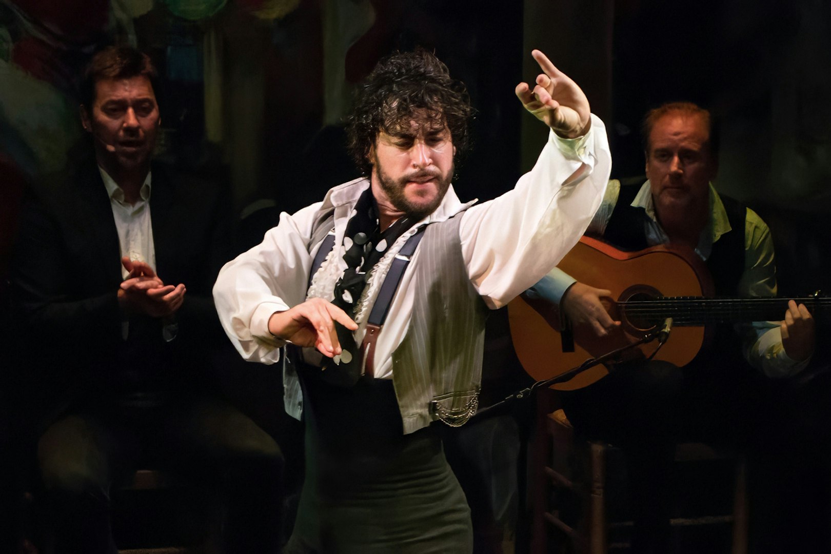 Flamenco dancer performing at Teatro Flamenco Triana with guitarist in background.