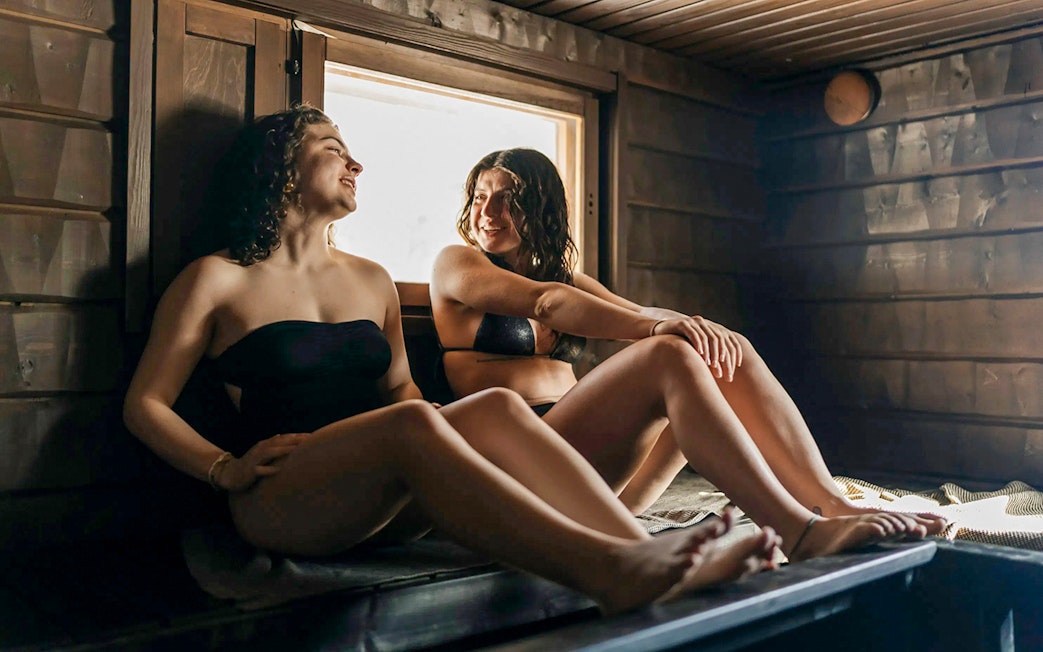 Guests relaxing in a sauna during Northern lights experience in Rovaniemi.