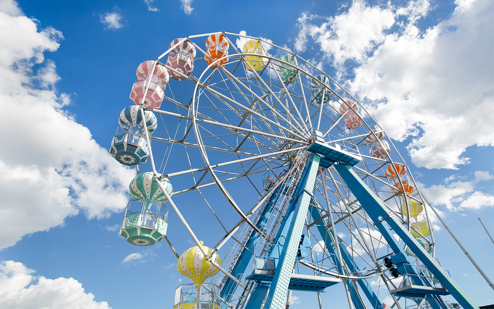 Ferris wheel with colorful gondolas against a blue sky at Old Town, Orlando.