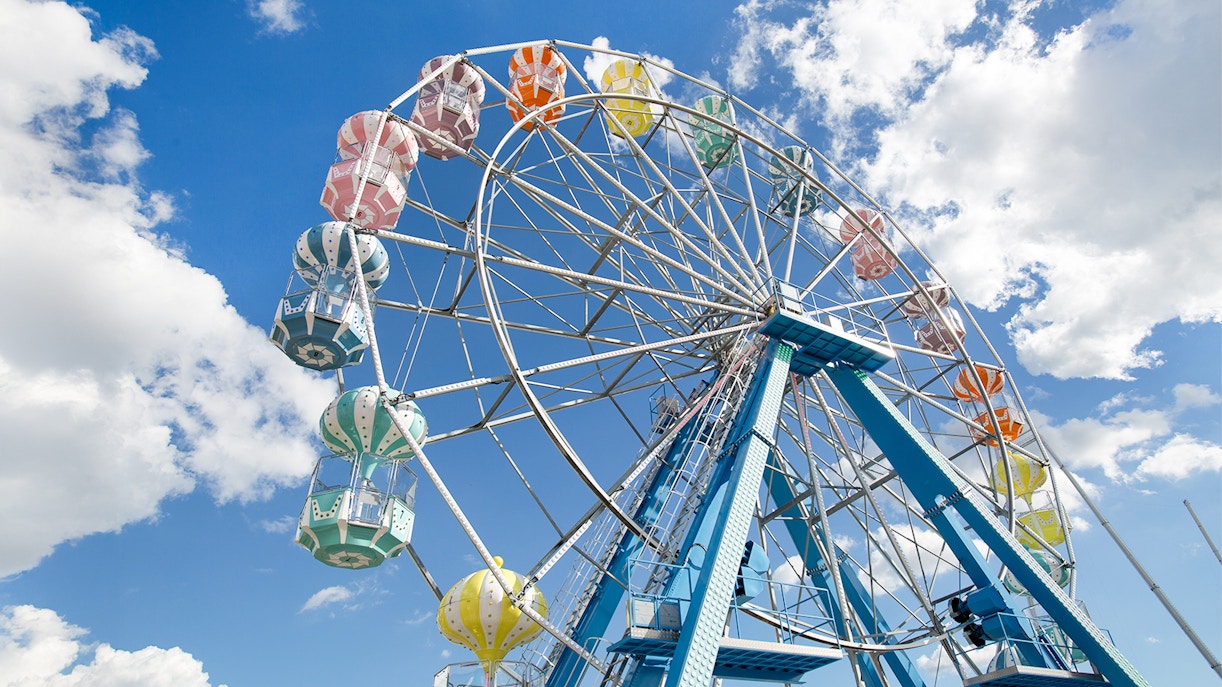 Ferris wheel with colorful gondolas against a blue sky at Old Town, Orlando.