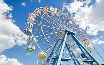 Ferris wheel with colorful gondolas against a blue sky at Old Town, Orlando.