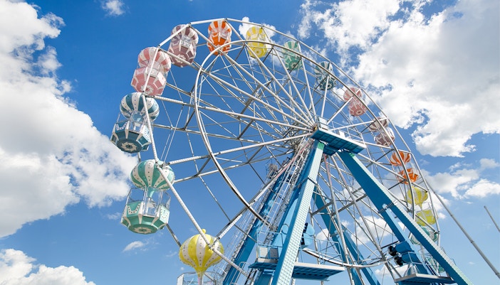 Ferris wheel with colorful gondolas against a blue sky at Old Town, Orlando.