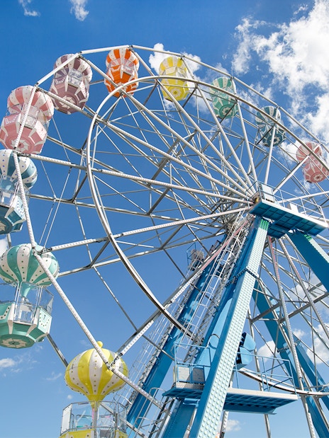 Ferris wheel with colorful gondolas against a blue sky at Old Town, Orlando.