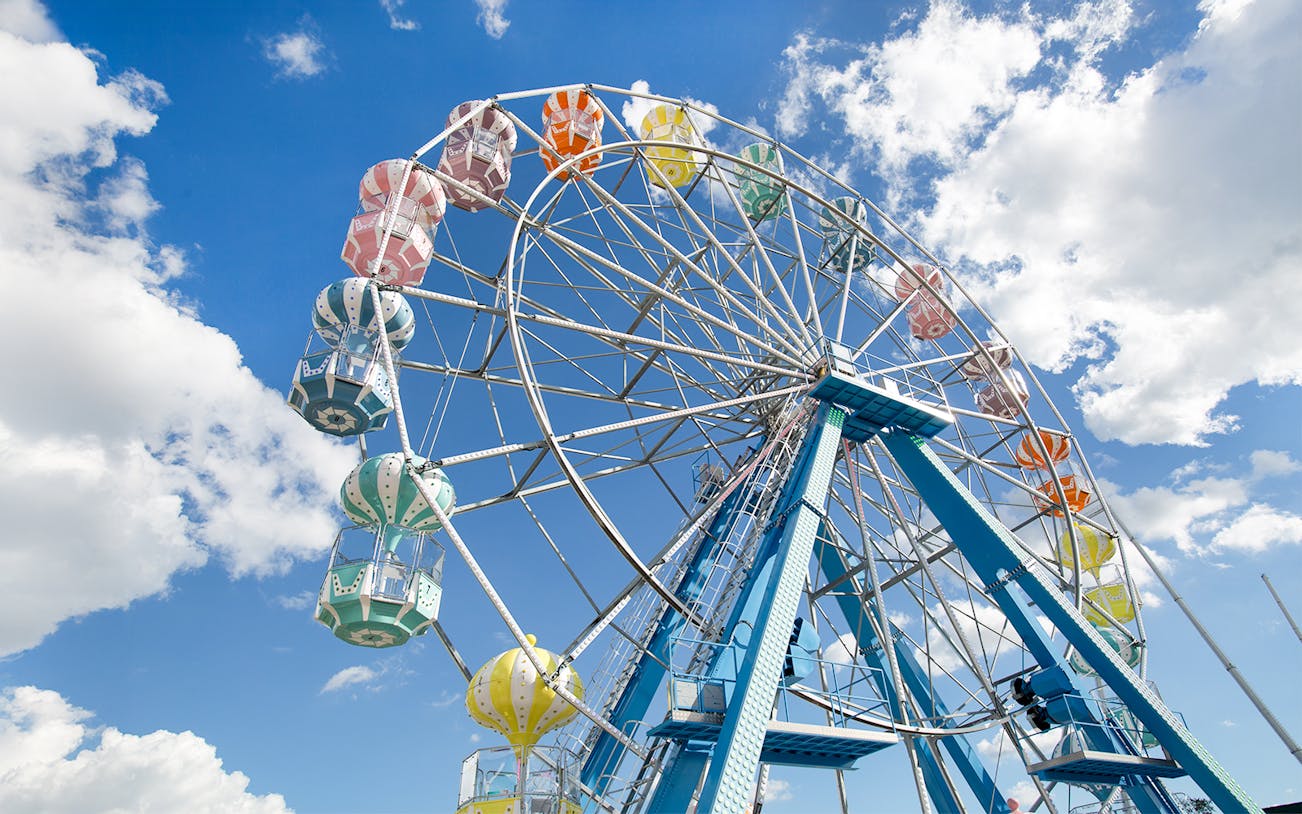 Ferris wheel with colorful gondolas against a blue sky at Old Town, Orlando.