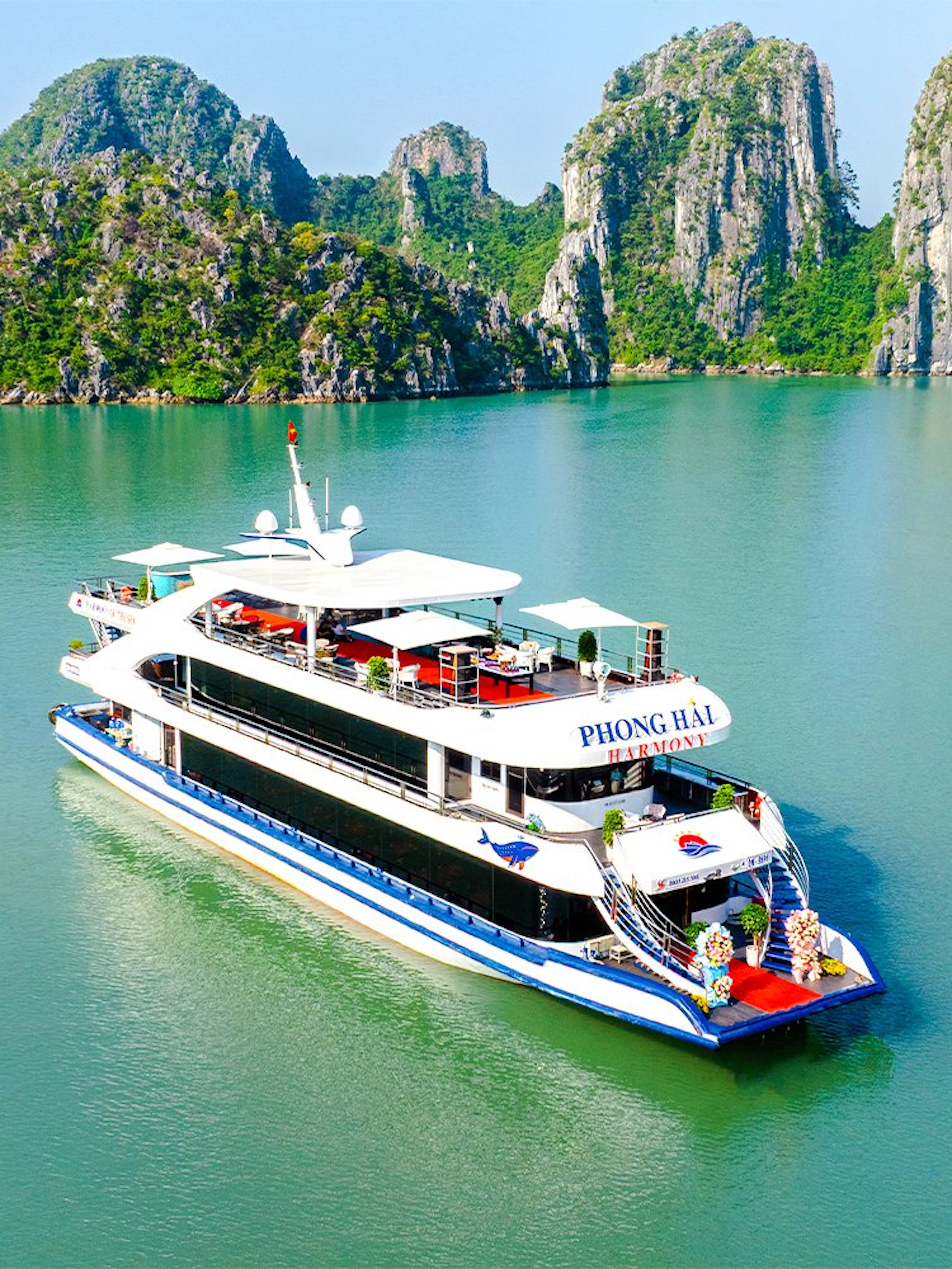 Delux Phong Hai Harmony Cruise sailing in Halong Bay with limestone karsts in the background.