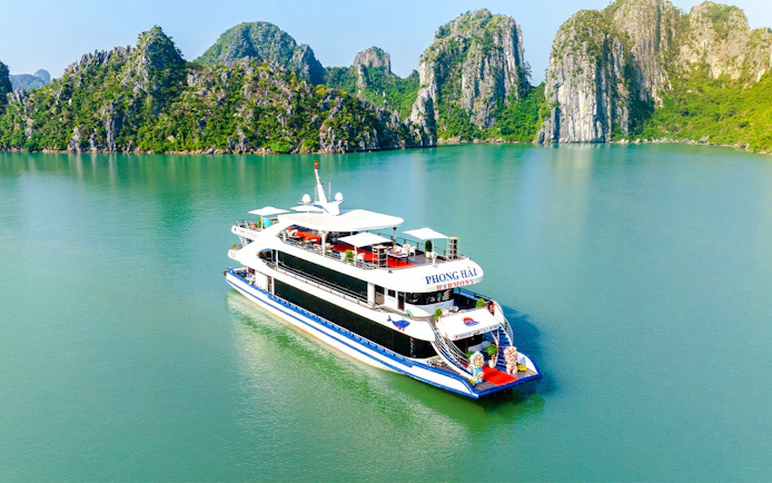 Delux Phong Hai Harmony Cruise sailing in Halong Bay with limestone karsts in the background.