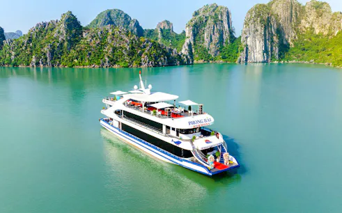Delux Phong Hai Harmony Cruise sailing in Halong Bay with limestone karsts in the background.