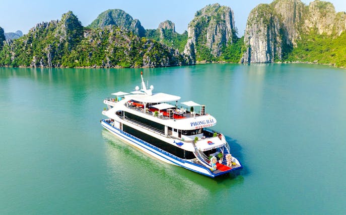 Delux Phong Hai Harmony Cruise sailing in Halong Bay with limestone karsts in the background.